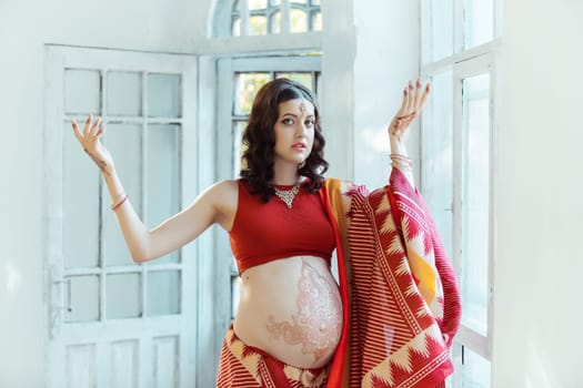 Indian picture on woman hands and pregnant belly with henna tattoo  on white room background