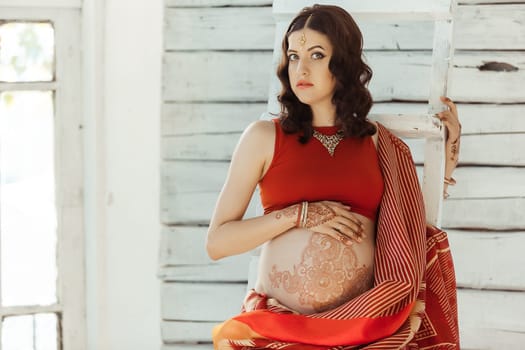 Indian picture on woman hands and pregnant belly with henna tattoo  on white room background
