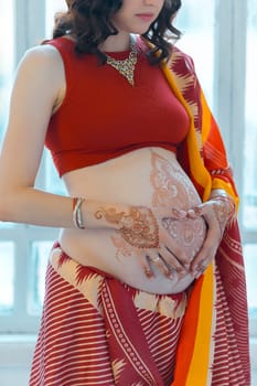 Indian picture on woman hands and pregnant belly with henna tattoo  on white room background