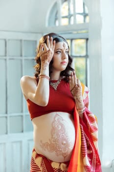 Indian picture on woman hands and pregnant belly with henna tattoo  on white room background