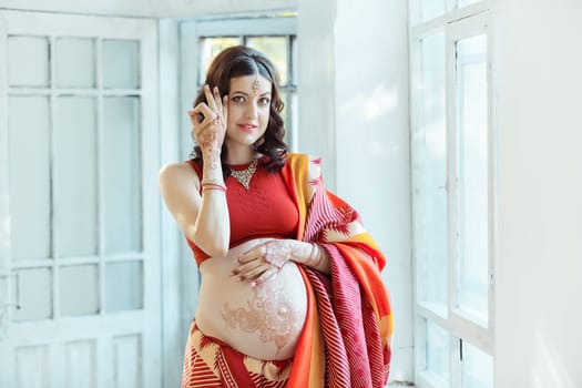 Indian picture on woman hands and pregnant belly with henna tattoo  on white room background