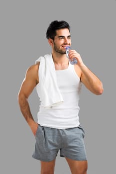 Handsome young man eating a healthy salad, isolated over a gray background