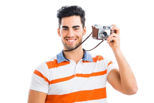 Handsome young man photographing with a vintage camera, isolated over gray background