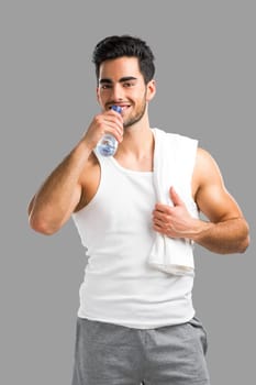 Handsome young man eating a healthy salad, isolated over a gray background