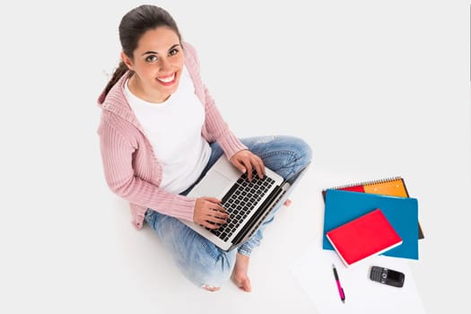 Young female student working with a laptop while drinking coffee, isolated over white background
