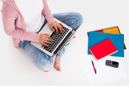 Young female student working with a laptop while drinking coffee, isolated over white background