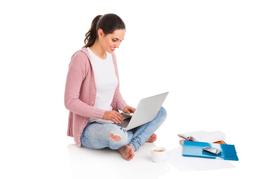 Young female student working with a laptop while drinking coffee, isolated over white background
