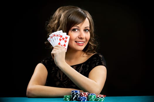 Young woman holding gambling chips on black background