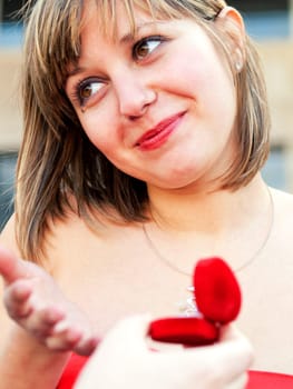 Young woman looking at her boyfriend proposing to her