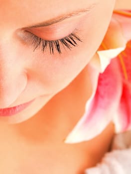 Young woman lying on white background with flowers in her hair waiting in spa studio for massage