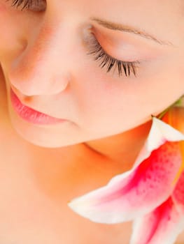 Young woman lying on white background with flowers in her hair waiting in spa studio for massage