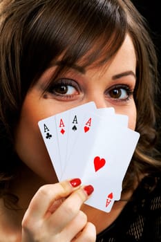 Young woman holding four aces in front of her face
