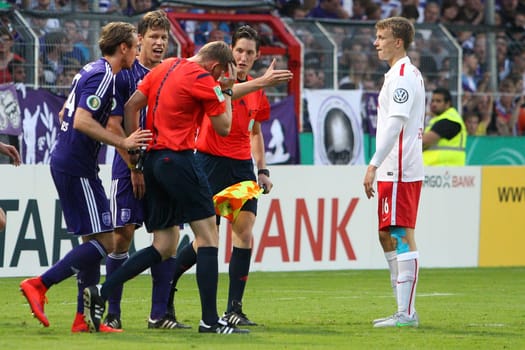Osnabrueck,Germany 01 August 2015:DFB Cup - 15/16 - VfL Osnabrueck vs. RB Leipzigv.li. Tobias Willers (Osnabrueck),Nicolas Feldhahn (Osnabrueck),referee Martin Petersen (Stuttgart) and Lukas Klostermann (RB Leipzig). Referee Martin Petersen (Stuttgart) grabs the lighter throw,Matthias Jöllenbec (Müllheim).
