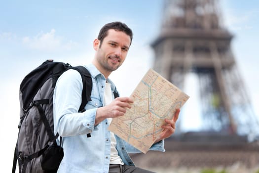 Young attractive tourist reading map in Paris, France
