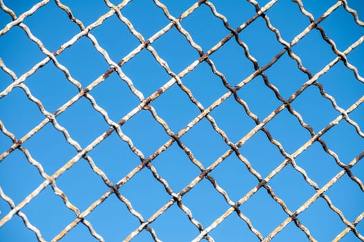 Old grunge fence net on blue sky background