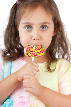 beautiful and cute little girl eating colorful lollipop and looking into the camera. Studio shot, isolated on white background