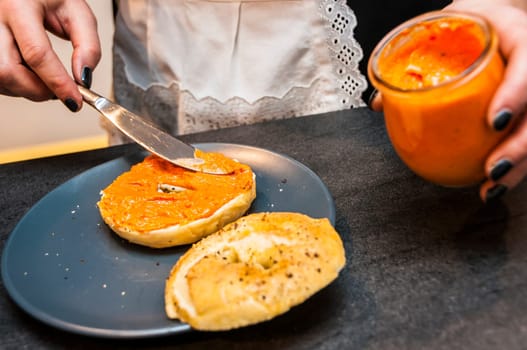 Woman applying delicious pumpkin spread on bread with a knife