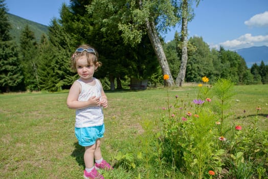 a pretty little girl playing with flowers in the garden and she look the camera