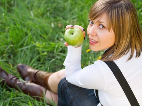 Teenage girl eating green apple outdoors