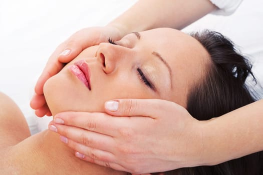 Young woman having a classical massage lying on white bed