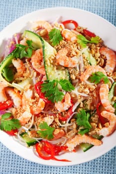 Asian salad with rice noodles, shrimps, peanuts, peppers, cucumber and cilantro