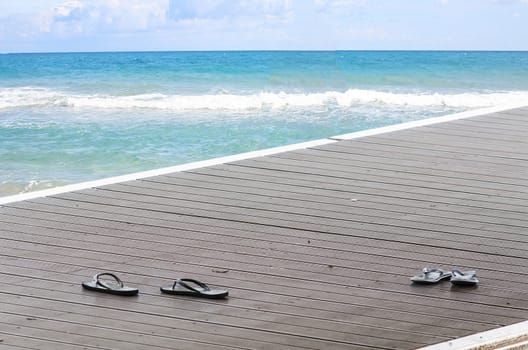 Black sandals on a jetty on a promenade by the lake.. In the background the blue sea.