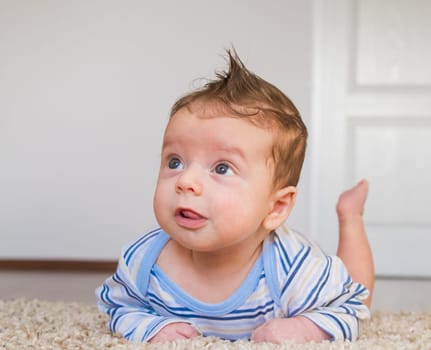 2 months old baby boy enjoying tummy time on the carpet at home.