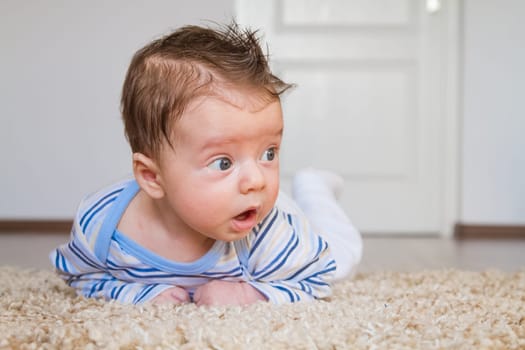 2 months old baby boy enjoying tummy time on the carpet at home.