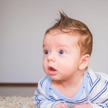 2 months old baby boy enjoying tummy time on the carpet at home.