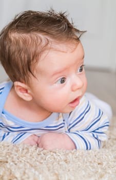 2 months old baby boy enjoying tummy time on the carpet at home.