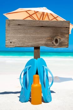 Flips flops stand in front of empty wooden sign on the beach