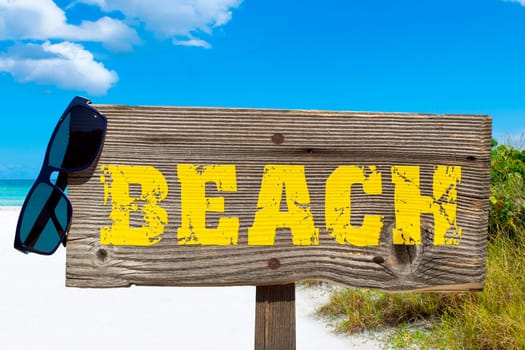 Wooden sign with the inscription "BEACH"" on the sandy beach"