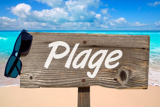 Wooden sign with the inscription "Plage"" on the sandy beach"