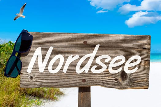 Wooden sign with the inscription "Nordsee"" on the sandy beach"