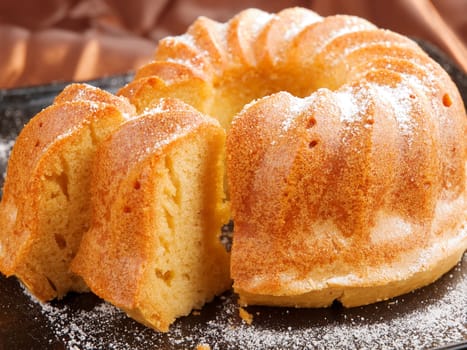 Vanilla cake with one piece of it on brown background
