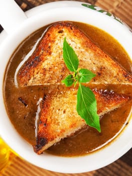 Famous onion soup with onions and olive oil in the background, close up