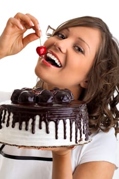 Young woman eating cherry from a chocolate cake, isolated on white