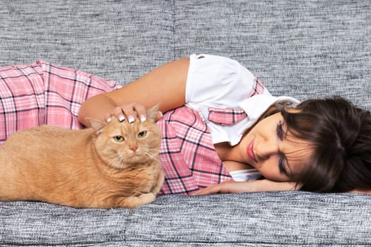 Young woman with cat lying on the sofa