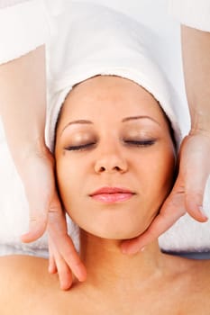 Young woman having a classical massage lying on white bed