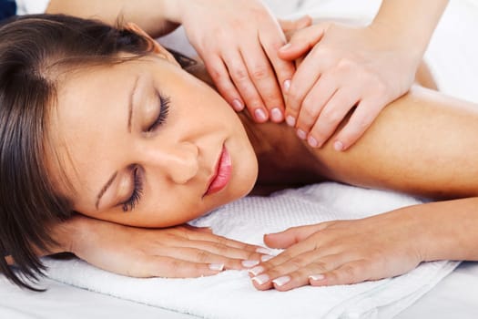 Young woman having a classical massage lying on white bed