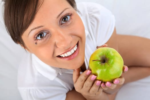 Young woman eating green apple isolated on white background