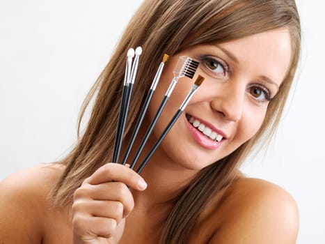 Close up of young woman face, holding all types of brushed in one hand