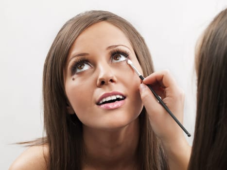 Applying make-up on young woman face, close up