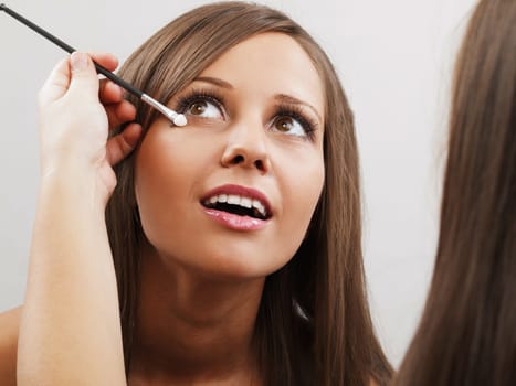 Applying make-up on young woman face, close up