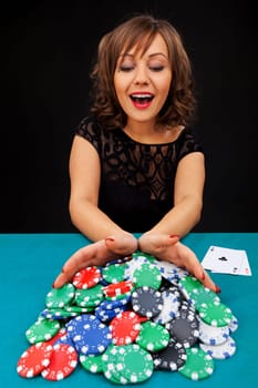 Young woman holding gambling chips on black background