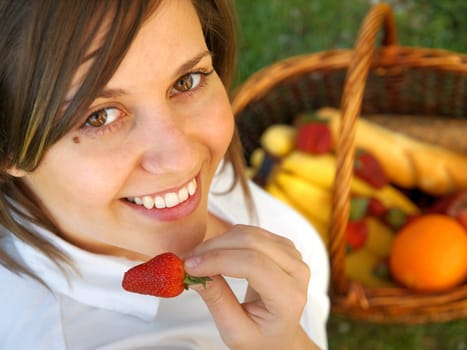 Young woman eating strawberry outdoors