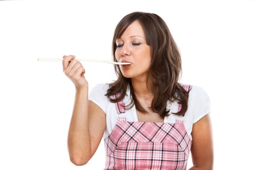 Young woman tasting sauce with a wooden spoon, isolated on white background