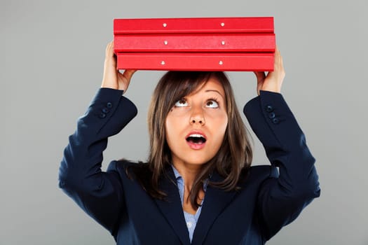 Businesswoman holding folders over her head isolated on gray background expressing emotion
