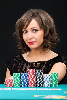 Young woman holding gambling chips on black background