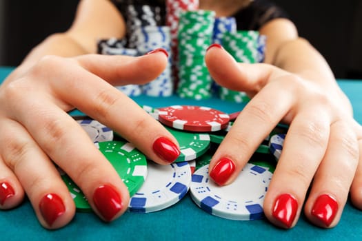 Young woman holding gambling chips on black background